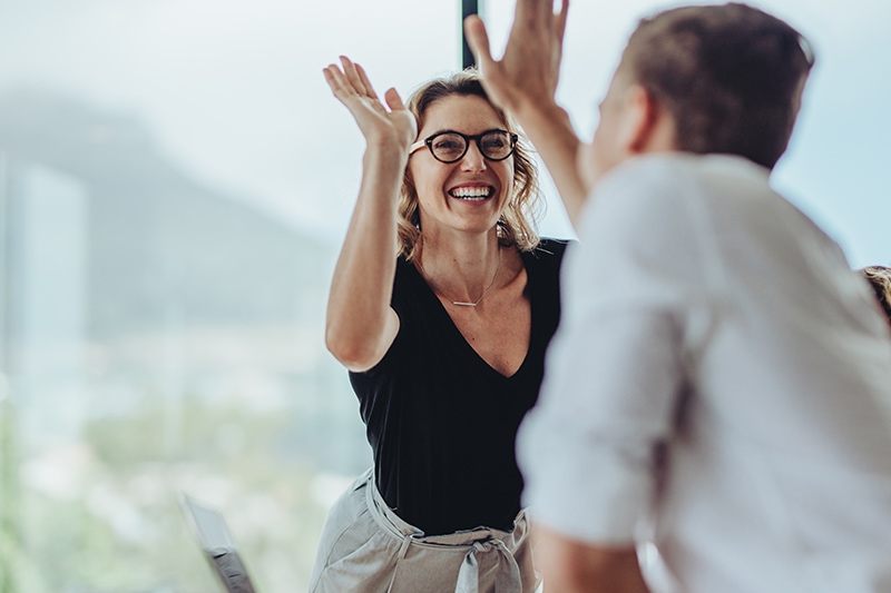 To kollegaer giver hinanden highfive efter effektiv rekruttering med IQ-test.